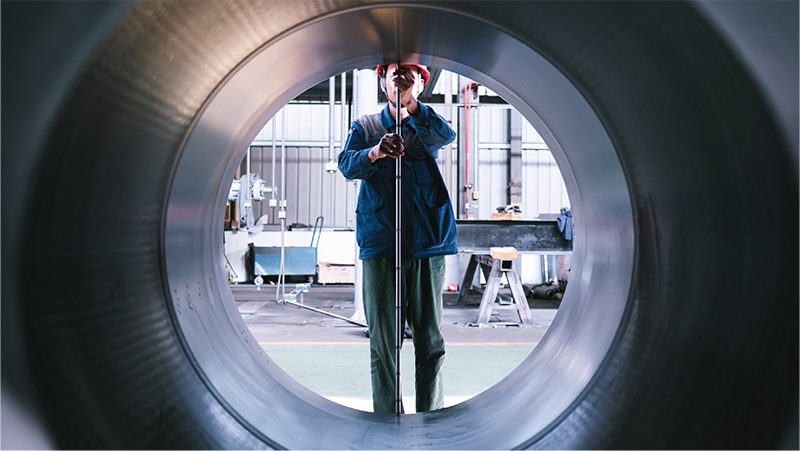 Inspector measuring a large machined cylinder